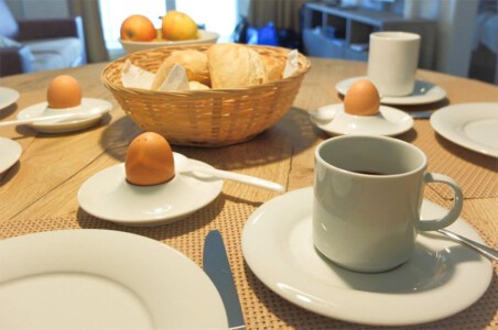 gedeckter Frühstückstisch mit Brötchen, Kaffee und Eiern